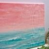 An abstract seascape acrylic painting featuring beautiful peach sunset sky with the horizon blending softly into the teal waters of the ocean.